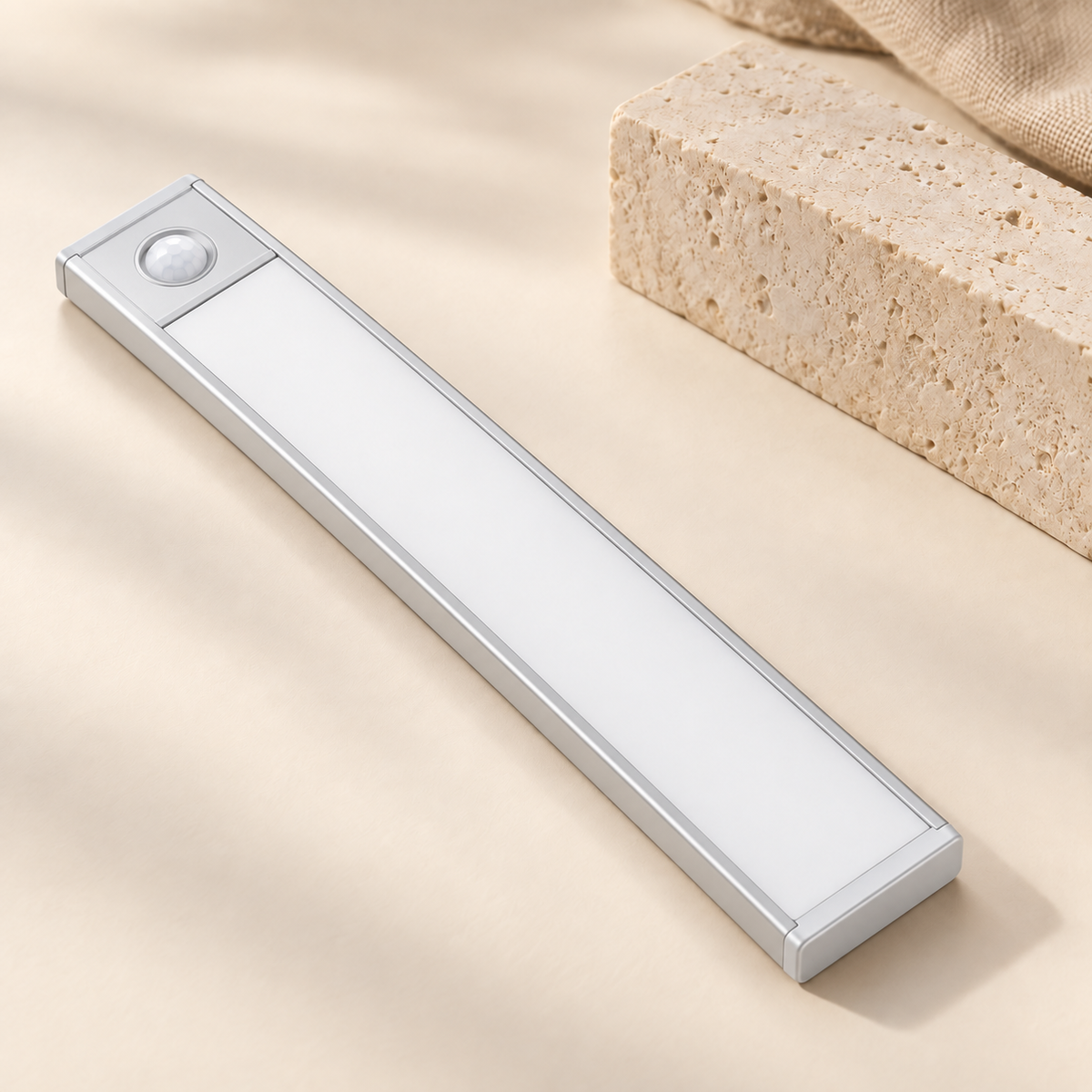 Silver 20 cm motion light on an ivory surface beside limestone and linen